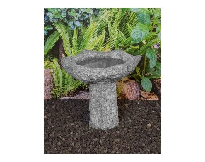 Grå 6-kantet fuglebad i granit på sokkel i have foran bregneblade